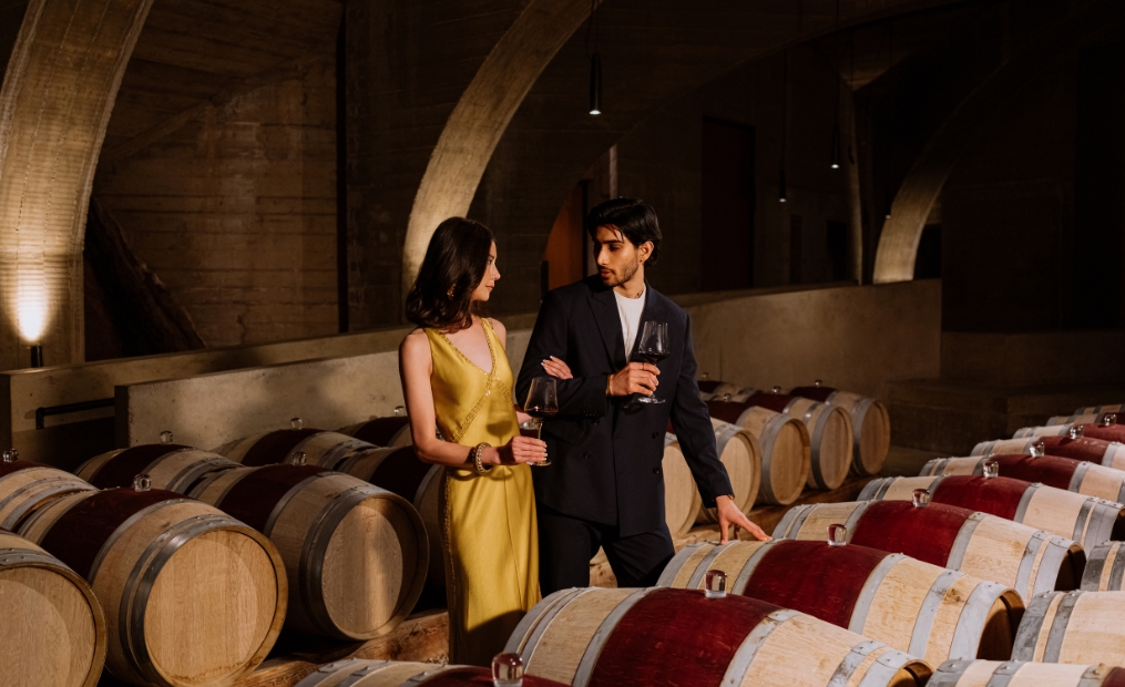 Guests enjoying a private wine tasting among French oak barrels in the underground cellar at Mission Hill Family Estate Winery, featuring premium Okanagan wines as part of an exclusive estate experience.