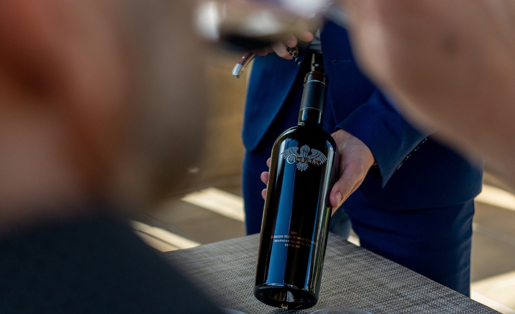 A personal wine ambassador presents a bottle of Oculus during a private tasting at Mission Hill Family Estate Winery, showcasing one of the winery's most iconic premium Okanagan wines.