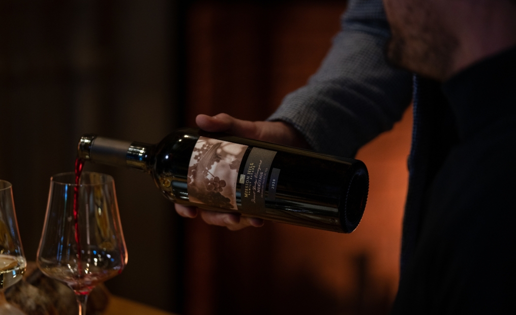 A designated host pours premium Terroir Okanagan red wine during a guided tasting at Mission Hill Family Estate Winery, part of an exclusive estate experience in West Kelowna.