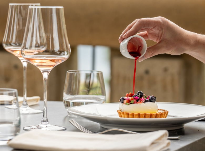A guest pouring estate berry sauce on a fruit tart paired with Exhilaration Brut Rose on the Terrace Restaurant