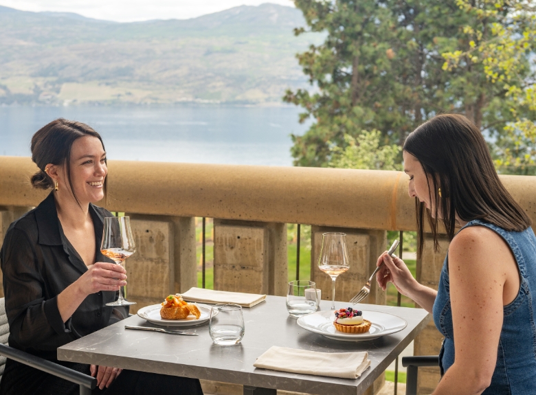 Guests enjoy food and wine on the Terrace at Mission Hill Family Estate Winery in West Kelowna, with panoramic views of Okanagan Lake and the surrounding valley.