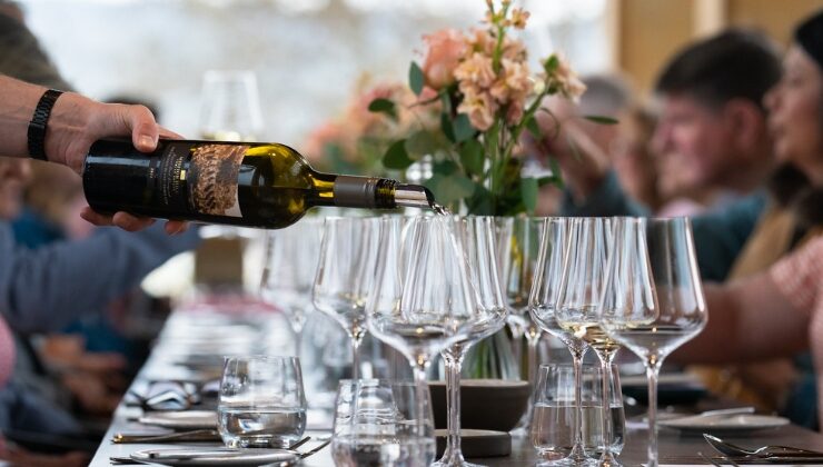 Wine is poured for guests gathered around a long dining table at Mission Hill Family Estate Winery in West Kelowna, showcasing a food and wine experience inspired by the Okanagan Valley.