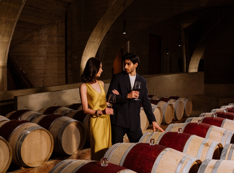 Guests enjoy wine in the barrel cellar at Mission Hill Family Estate Winery in West Kelowna, offering an immersive winery tour and tasting experience among aging barrels.